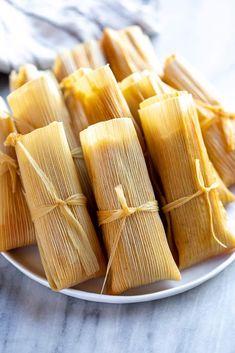 tamales tied up on a white plate