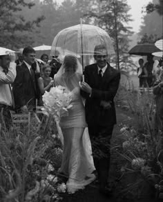 a bride and groom walking under an umbrella