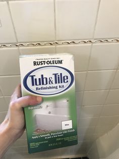 a person holding up a box of tub and tile cleaning kit in a bathroom stall