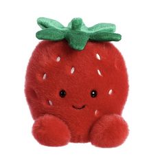 a red stuffed strawberry with a green bow on it's head, sitting against a white background