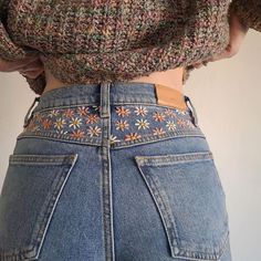 the back of a woman's jeans with flowers on it and an embroidered belt