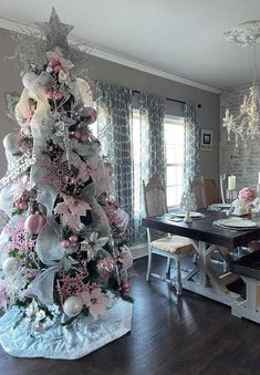 a decorated christmas tree in the middle of a dining room with white chairs and table