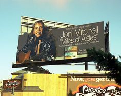 a billboard with an image of a woman holding a guitar on it's side