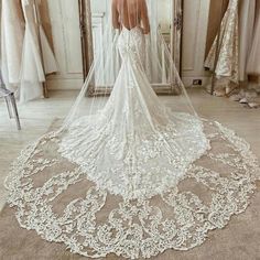 a woman is standing in front of a mirror wearing a wedding dress with a long veil