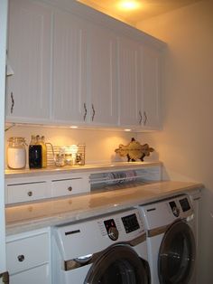 a washer and dryer in a small room with white cabinets on the wall