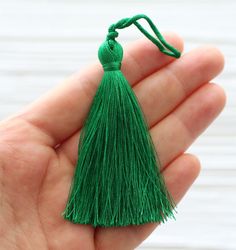 a hand holding a small green tassel