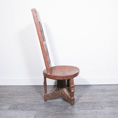 a wooden chair sitting on top of a hard wood floor next to a white wall