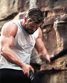 a man holding a tennis racquet while standing next to a rock face wall