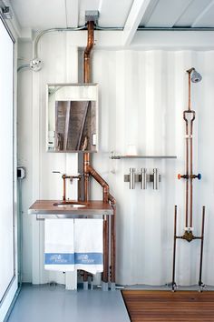 a room with pipes, sink and mirror on the wall next to wooden flooring