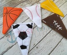 four pennants with different designs on them sitting on a wooden surface, one has a basketball and the other has a basketball