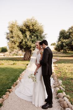 a bride and groom standing in front of a tree