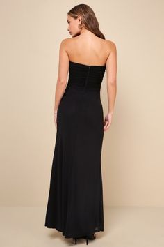 a woman in a black dress is looking back at the camera and she has her hands on her hips