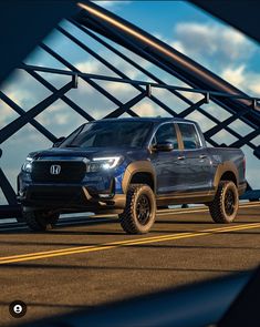 a blue truck driving down a road next to a bridge