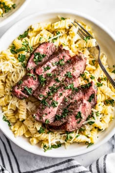 two white bowls filled with pasta and meat topped with parsley on the top one