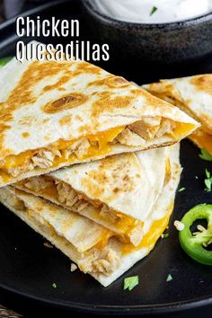 chicken quesadillas on a black plate with jalapenos