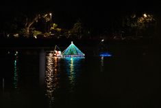 a boat with christmas lights on it floating in the water