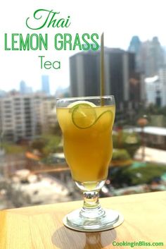 there is a glass with lemon grass tea on the table in front of a cityscape