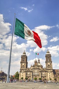 the mexican flag is flying in front of an old building