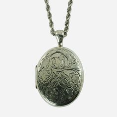 "This vintage sterling silver locket pendant and necklace set was made by highly regarded jeweler, Danecraft.  The large oval locket features engraved decoration on the front consisting of multiple ivy leaves growing along curvilinear stems, all of which are set against a stippled ground.  There is a trio of ivy leaves at the bottom with four c-shaped scrolls positioned around them.  The scrolls have a series of interior rectangular shapes that give them the appearance of stylized thistle blosso Classic Oval Pendant Jewelry With Engraving Option, Antique Oval Jewelry With Polished Finish, Heirloom Oval Engraved Locket Necklace, White Gold Oval Link Locket Necklace, Antique Oval Pendant Jewelry With Polished Finish, Heirloom Oval Link Necklace With Polished Finish, Heirloom White Gold Oval Pendant Necklace, Classic Oval Engraved Necklaces, Classic Oval Engraved Necklace