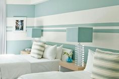 two beds in a room with blue and white striped walls