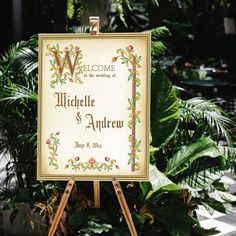 a welcome sign is displayed on an easel in front of some plants and greenery