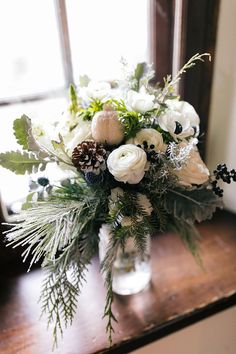 a vase filled with white flowers and greenery