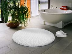 a bathroom with a bathtub, toilet and rug on the floor next to it