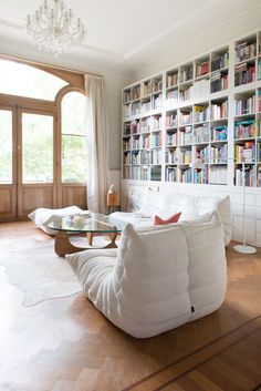 a living room filled with white furniture and bookshelves