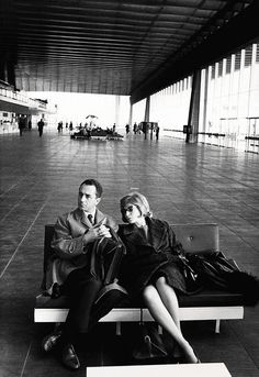 a man and woman sitting on a bench in an airport