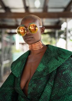 a woman with sunglasses on her head wearing a green dress and gold choker necklace