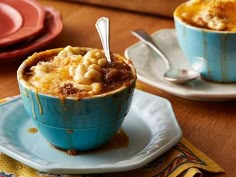 two cups filled with macaroni and cheese on top of plates