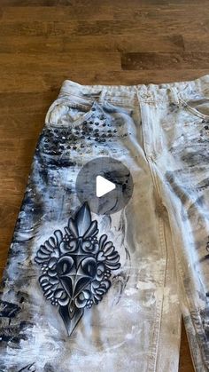 a pair of white shorts with black and grey designs on them sitting on a wooden floor