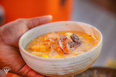 a person holding a bowl of soup in their hand