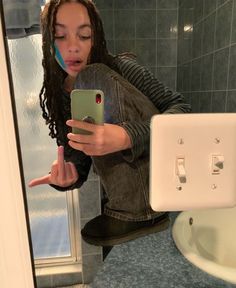 a woman taking a selfie with her cell phone in front of a bathroom mirror