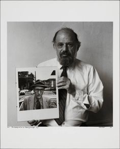 black and white photograph of man holding up an old photo