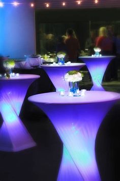 purple lighted tables with vases and flowers on them