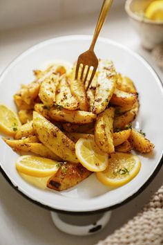 a white plate topped with fried potatoes and lemon wedges