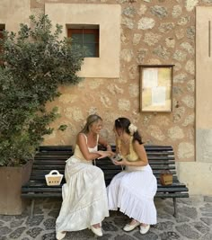 two women sitting on a bench talking to each other