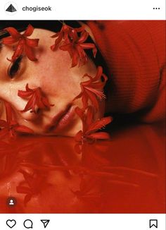 a woman with red flowers on her face and eyes is laying down in the water