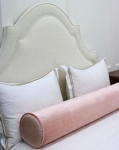 a bed with two pillows on top of it and a pink pillow under the headboard