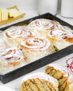 a pan filled with cinnamon rolls on top of a table next to other desserts