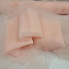 several pieces of pink tulle sitting on top of a white sheeted bed spread