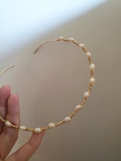 a hand is holding a gold necklace with pearls