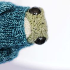 a close up of a knitted object with two buttons on the end of it