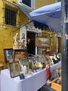 there is a table that has pictures and other items on it in front of a building