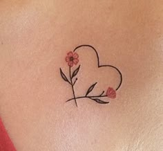 a small heart shaped tattoo with flowers on the back of a woman's shoulder