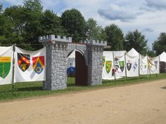 there are many flags hanging on the fence by the road and in front of it is a stone gate