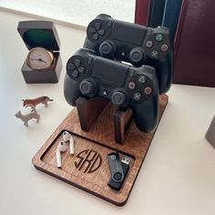 two video game controllers are on a wooden stand next to other items and a clock