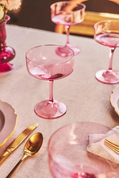 the table is set with pink wine glasses and gold cutlery, along with silverware