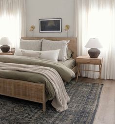 a large bed sitting next to two lamps on top of a wooden table in a bedroom